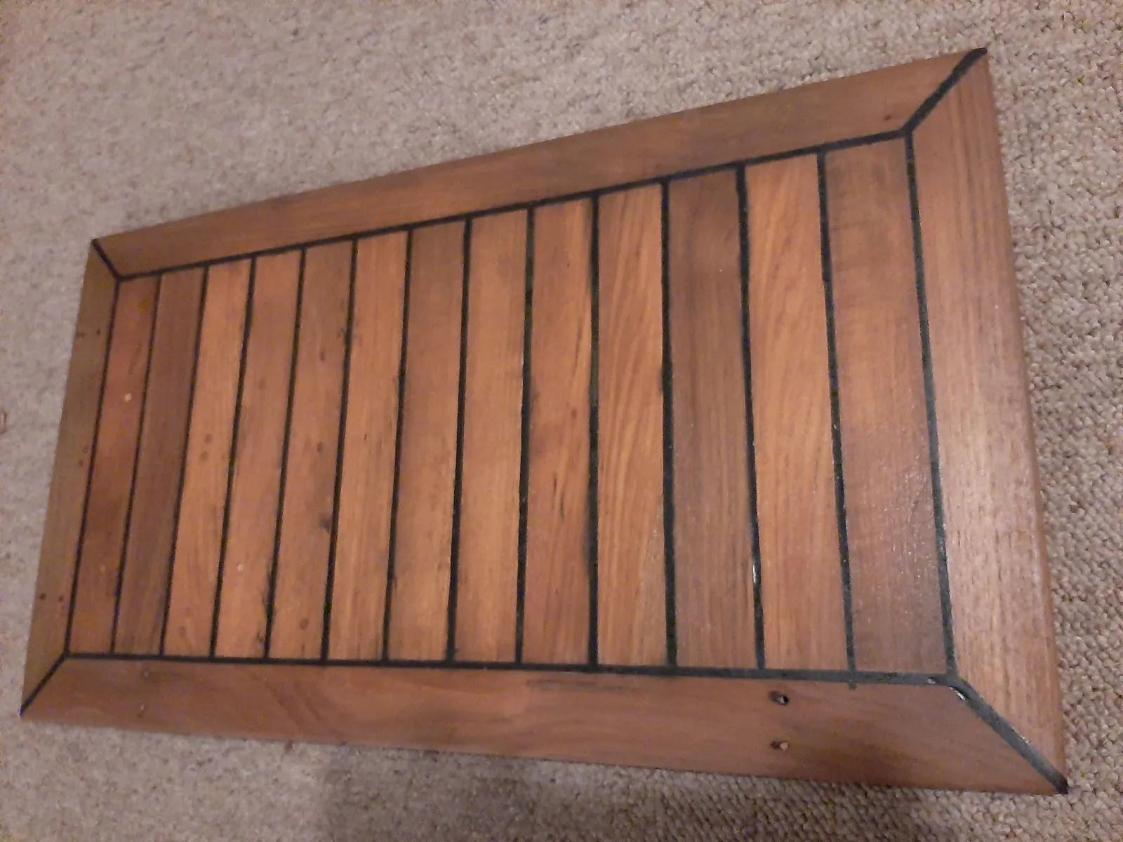 A rebuilt teak hatch panel, revarnished, with recaulked seams