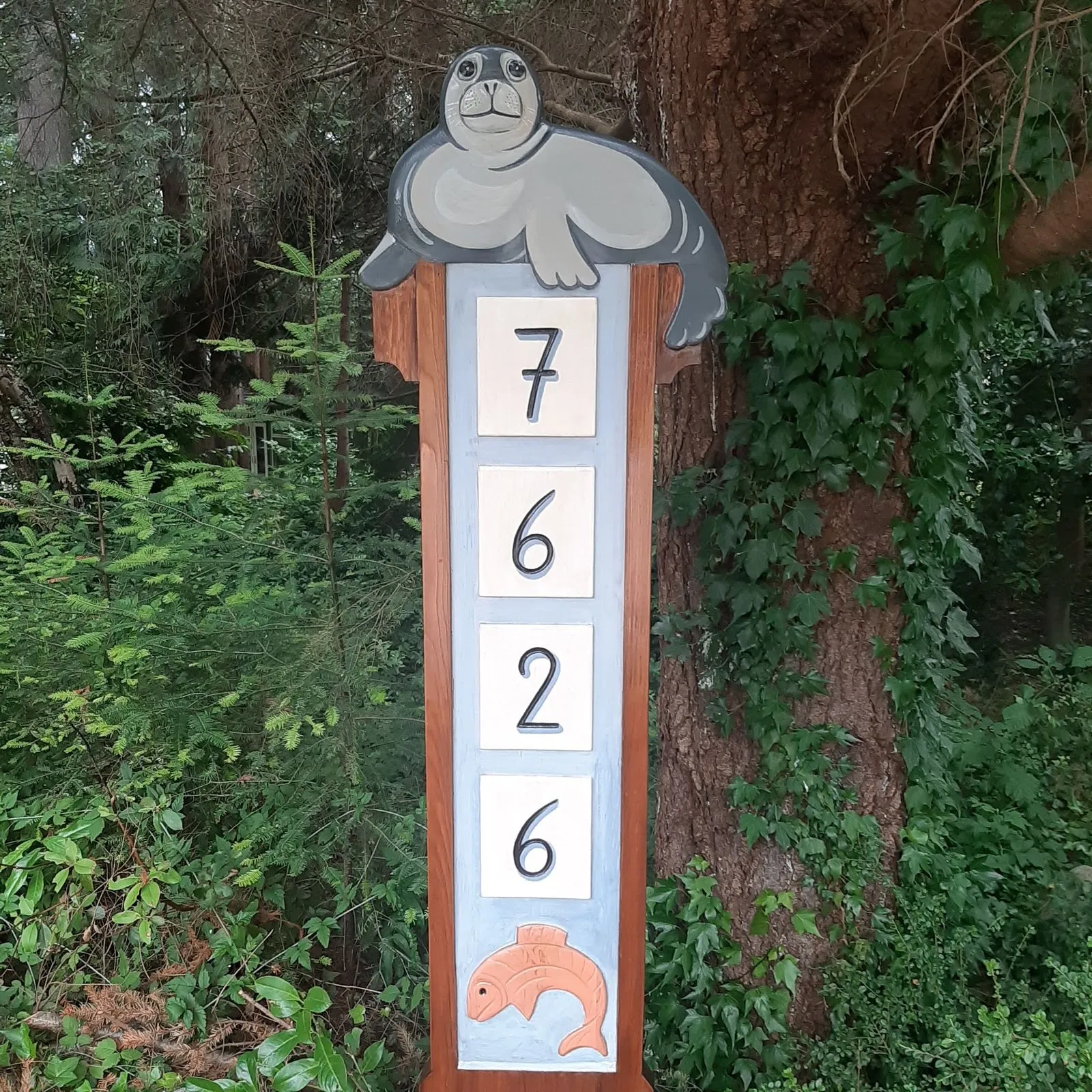 A carved and painted house-number sign topped with a carved seal
