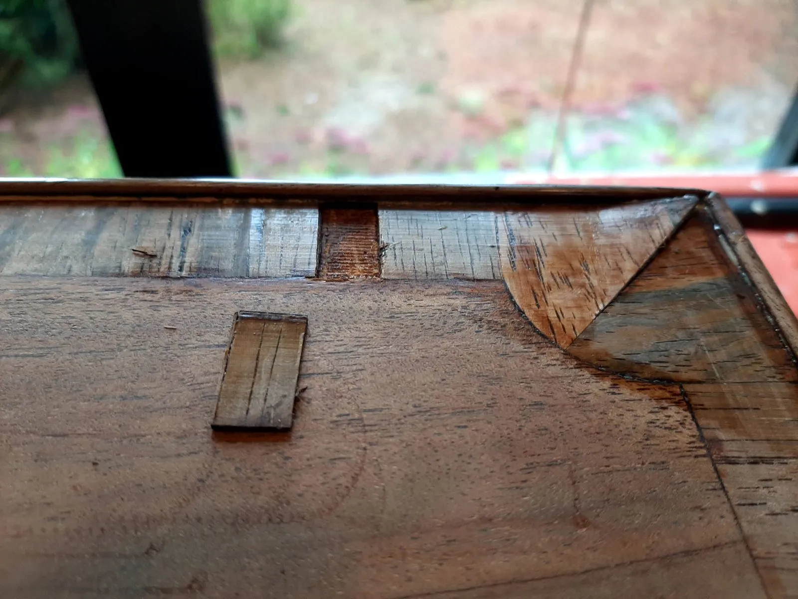 Close detail of damaged and missing veneer on the chest of drawers