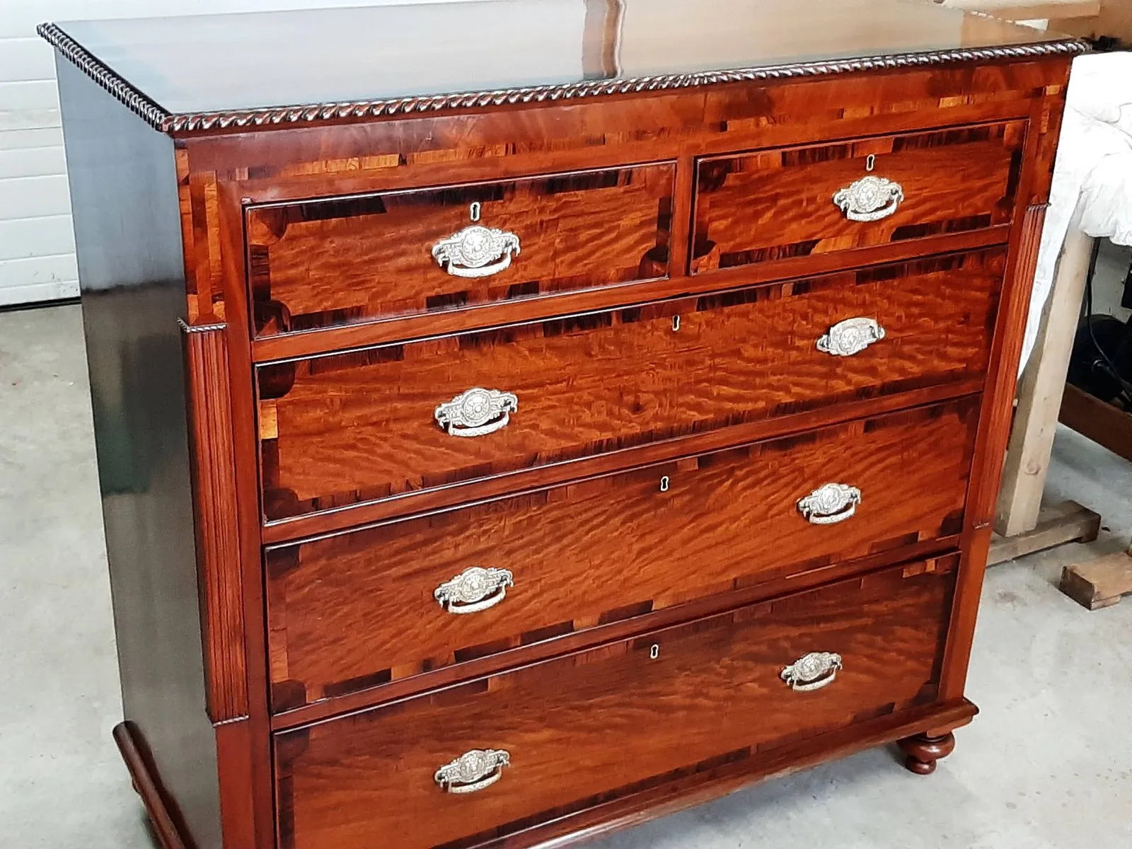 A restored mahogany chest of drawers, polished, with brass handles refitted